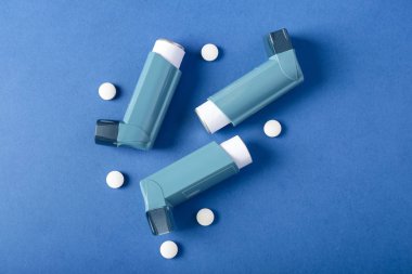 Inhalers and pills on color background clipart