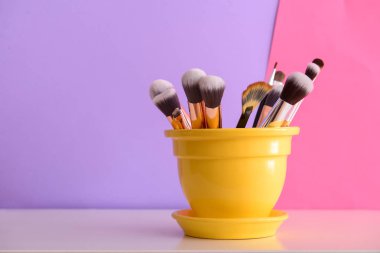 Pot renk duvarının yakınında tuvalet masasının üzerinde makyaj fırçaları ile