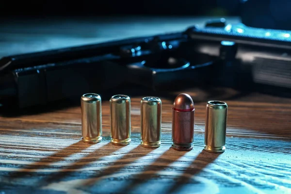 Bullets with gun on wooden table
