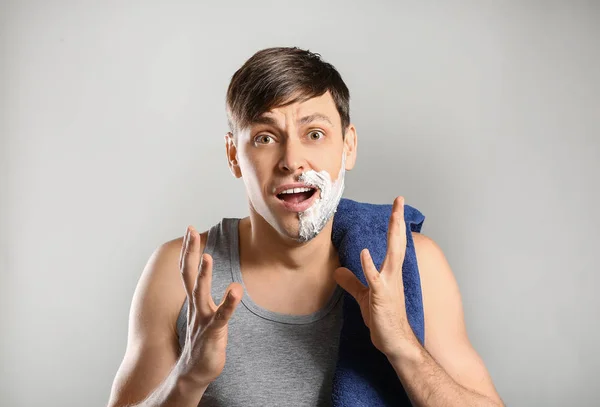 Shocked man having half of his face shaved against grey background