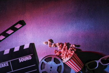 Film clapper, patlamış mısır ve gri arka plan üzerine gözlük ile film reel
