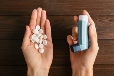 Oksijen tüpü ve astım ahşap arka plan üzerinde karşı hapları ile eller