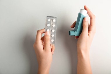 Oksijen tüpü ve astım ışık arka plan üzerinde karşı hapları ile eller