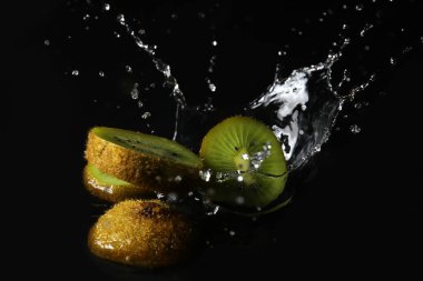 RIPE kivi su sıçrama ile koyu arka plan üzerinde kesmek.