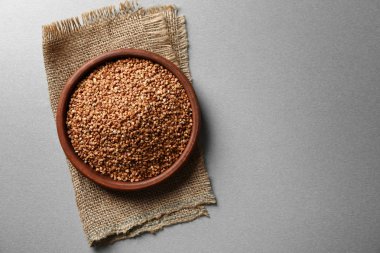 Gri arka plan üzerinde ham buğday ile kase