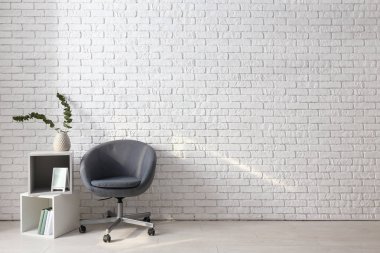 Rahat koltuk ve raf ünitesi beyaz duvara yakın