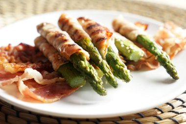 Plaka lezzetli pastırma ile kuşkonmaz masada, closeup sarılmış.