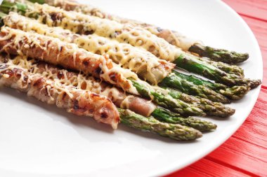 Ahşap masa, closeup kuşkonmaz lezzetli domuz pastırması ile plaka sarılmış