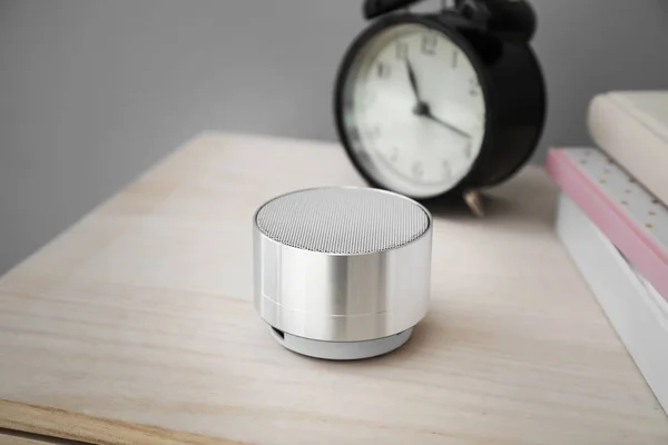 Smart home assistant device and clock on table against grey background