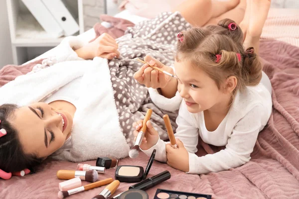 かわいい娘と母親のベッドに横になっている化粧品 — ストック写真