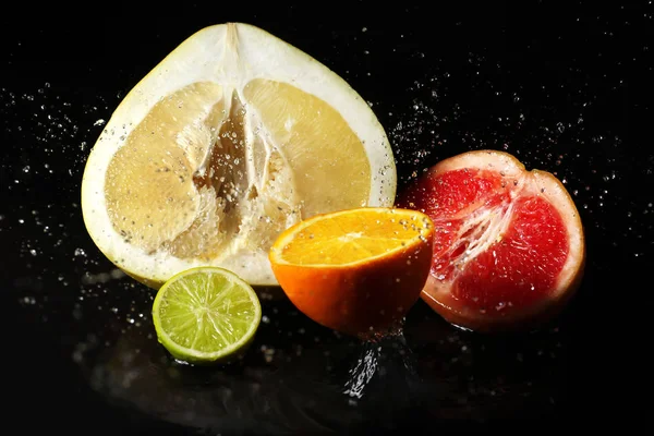 Ripe cut fruits with water splash on dark background