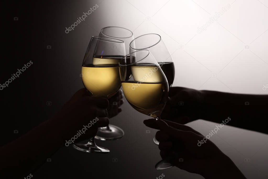 Women clinking glasses with tasty wine on dark background