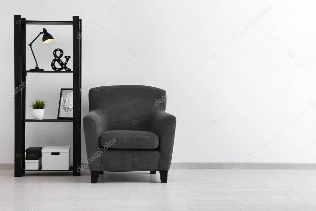 Comfortable armchair and shelf unit near white wall