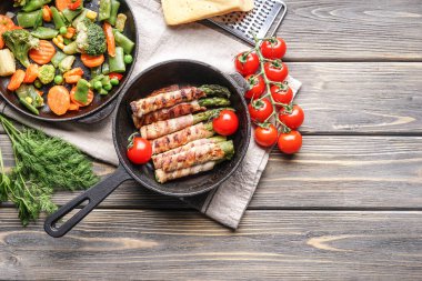 Ahşap masa üzerinde tavada kuşkonmaz lezzetli domuz pastırması ile kompozisyon sarılmış