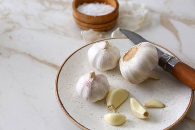 Hafif arka planda taze sarımsaklı tabak.