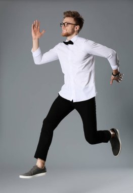 Moda bir genç adam gri arka plan üzerinde atlama