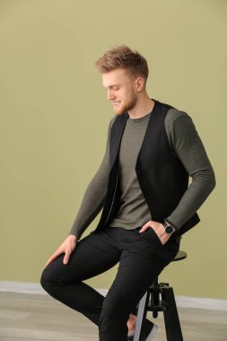 Dışkı rengi duvara oturan moda genç adam