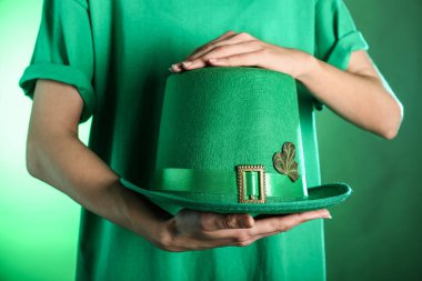 Yeşil şapka renk arka plan üzerinde tutan genç kadın. Aziz Patrick günü kutlama