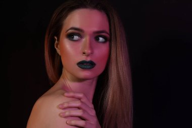 Güzel genç kadın koyu arka plan üzerinde parlak makyaj ile