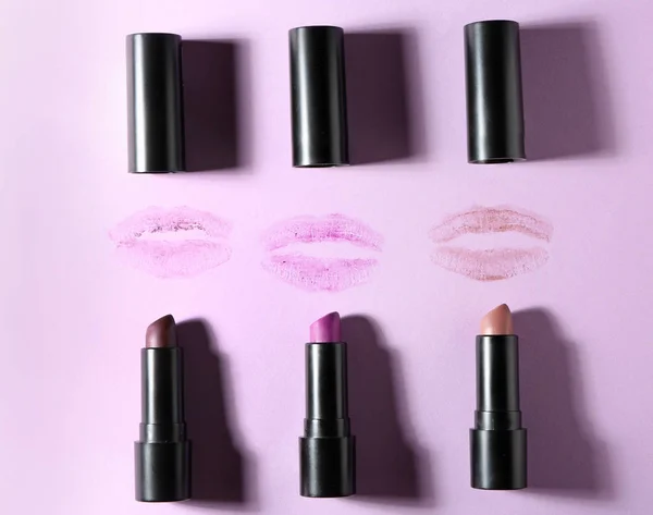 Different lipsticks and lip prints on color background