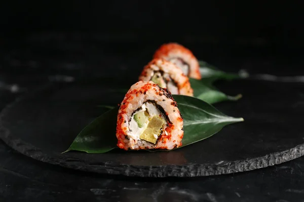 Tasty sushi rolls on slate plate