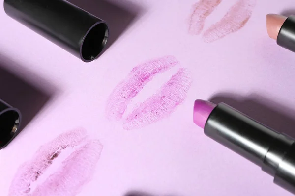 Different lipsticks and lip prints on color background