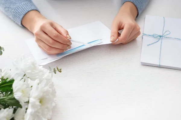 Young woman opening envelope with letter at table