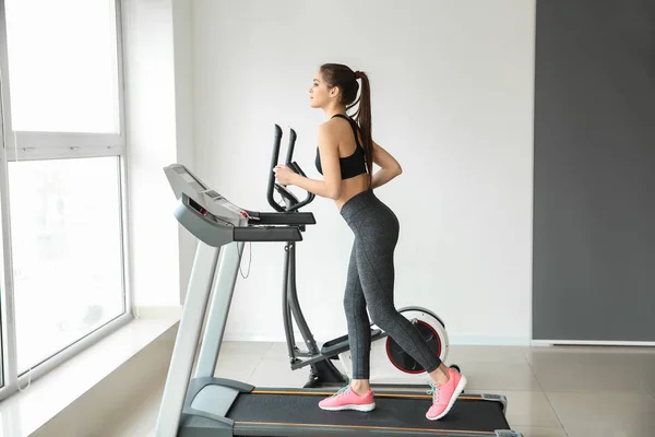 Sporty young woman on treadmill in gym