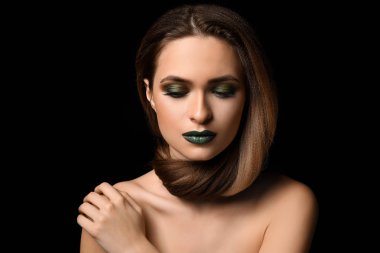 Güzel genç kadın koyu arka plan üzerinde parlak makyaj ile