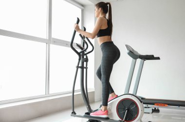 Spor salonunda modern makine kullanan sportif genç kadın