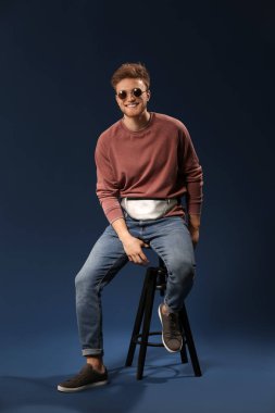 Dışkı rengi arka plan üzerinde oturan moda genç adam