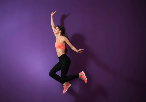 Sportieve Jonge Vrouw Springen Tegen Een Achtergrond Met Kleur — Stockfoto
