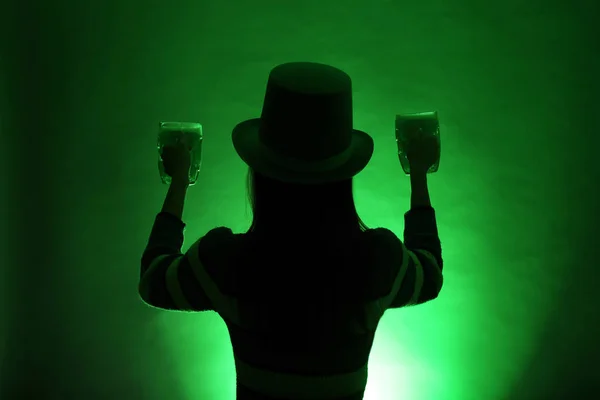 Silhouette of woman with beer on dark color background. St. Patrick\'s Day celebration
