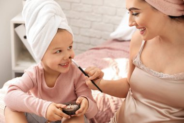 Genç anne kozmetik yüzü sevimli kızı evde üzerine uygulama