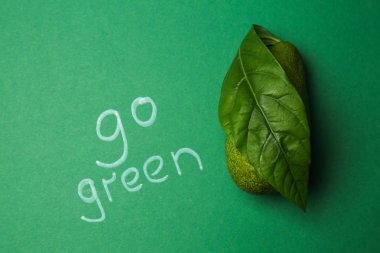 Metin Go Green taze yaprak ve avokado renkli arka plan üzerinde