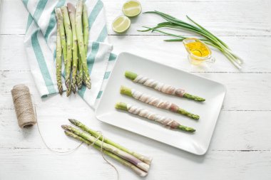 Plaka pastırma ile kuşkonmaz beyaz masaya sarılmış.