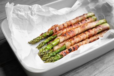 Pastırma ile pişirme çanağı kuşkonmaz ahşap masanın üzerine sarılmış.