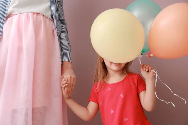 母亲与可爱的小女儿拿着气球在颜色背景 — 图库照片