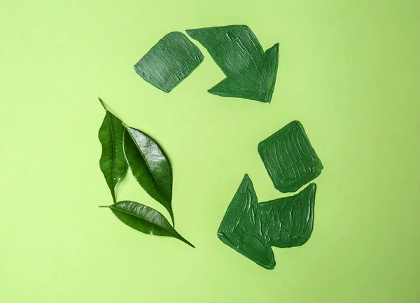 Recycling sign with leaves on color background. Ecology concept