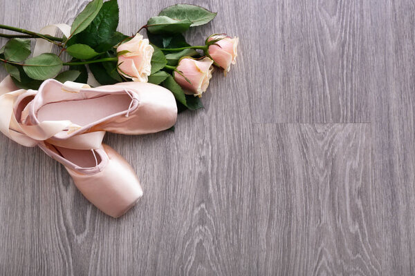 Ballet shoes with roses on wooden floor