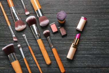 Ahşap arka plan üzerinde kozmetik ile profesyonel makyaj fırçaları