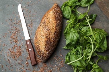 Keten tohumu ve gri arka plan üzerinde fesleğen ile lezzetli ekmek