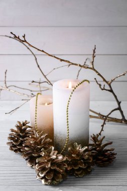 Beyaz masaya yanan mumlar ve altın koniler ile güzel kompozisyon