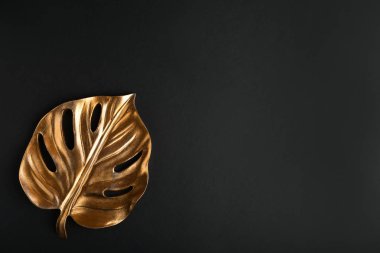 Koyu arkaplanda altın tropikal yaprak