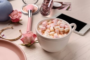 Sıcak kakao marshmallows ve beyaz masada kadın aksesuarları ile fincan