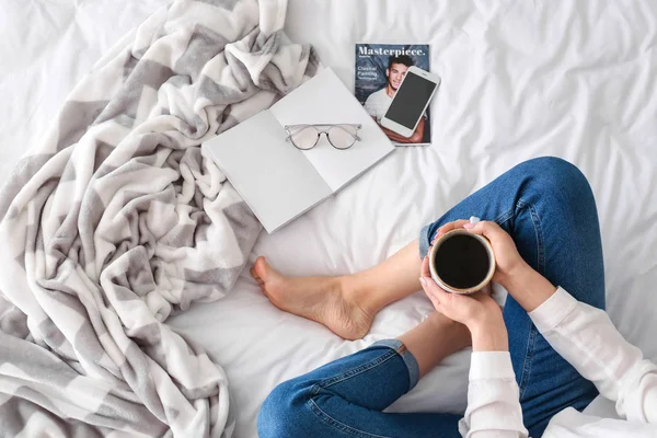 Young woman drinking coffee on bed in morning