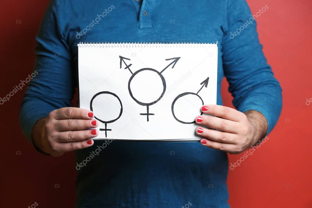 Man with manicure showing male, female and transgender's symbols on color background, closeup