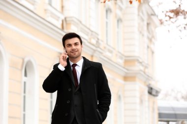 Yakışıklı genç işadamı tarafından cep telefonu açık havada konuşuyor