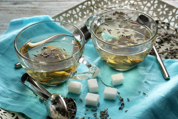 Glass cups of hot tea with sugar on tray