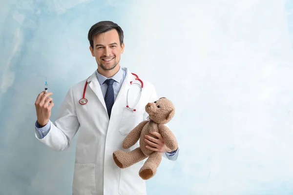 儿科医生与玩具熊和注射器在颜色背景 — 图库照片